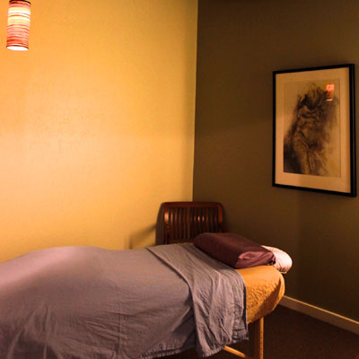 Acupuncture treatment room at East West SF Glen Parks in San Francisco with massage table, chair and artwork.